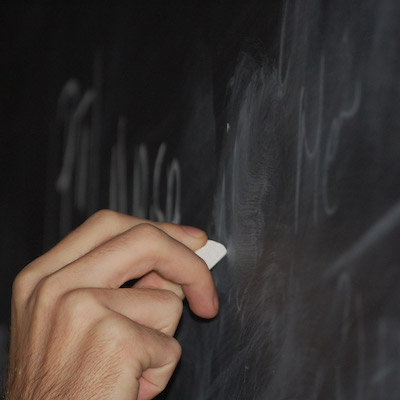 hand with chalk writign on blackboard